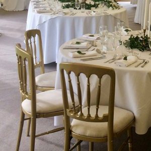 Gilt gold spindle back banqueting chairs with ivory seat pads and ivory table linen