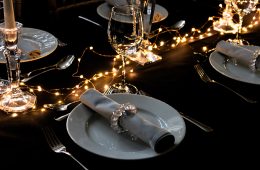 Party table settings with black cloths, grey napkins and fairy lights