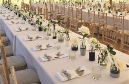 July wedding with small glass bottles, spirit glasses and banquet dining with white table linen