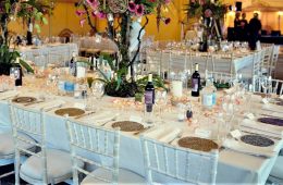 Colourful table settings in an Indian lined marquee, with bright flowers and finer range of tableware