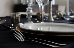 An ivory plate on a black cloth, with silver cutlery