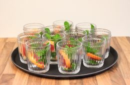 A black bar tray with ribbed cocktail glasses filled with fruit and mint leaves