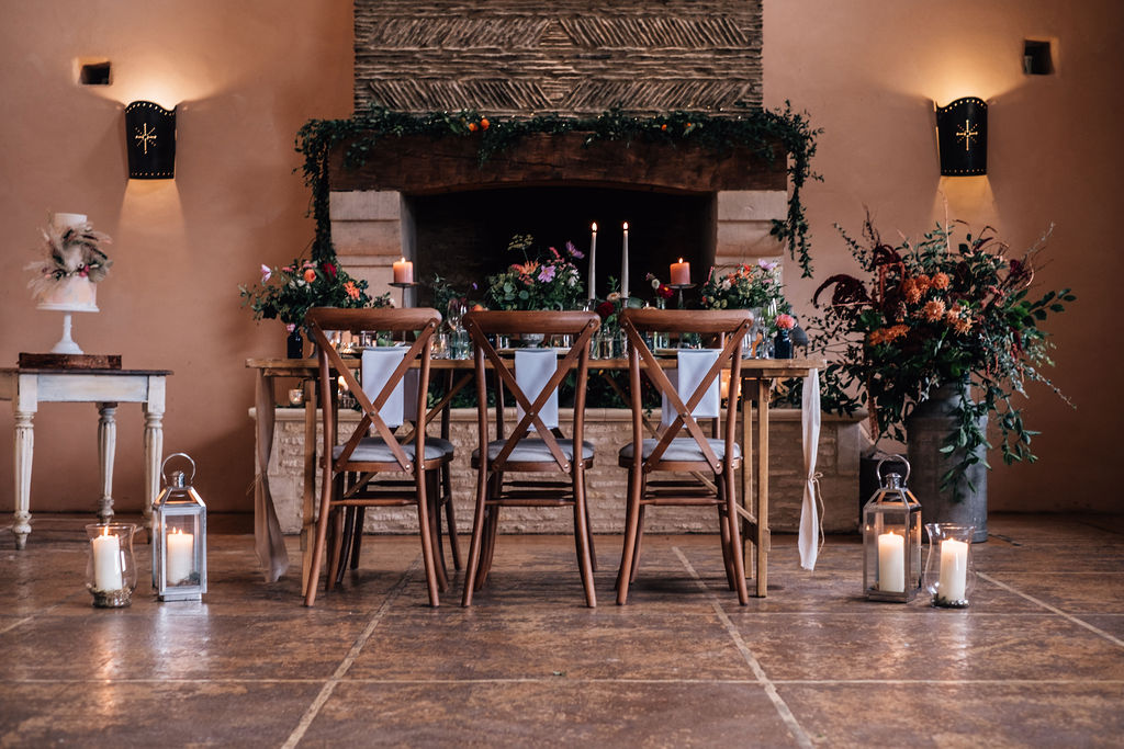Wide rustic wooden trestle tables with botanical theme, white pillar candles and ivory crockery